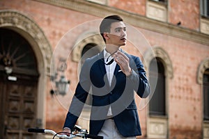 Young elegant businessman with bicycle on the street