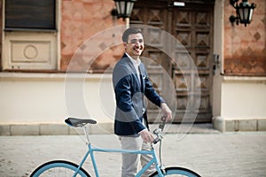 Young elegant businessman with bicycle on the street