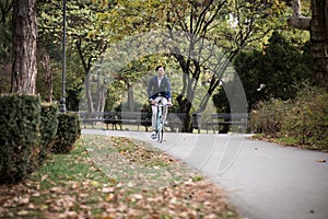 Young elegant businessman traveling to work by bicycle