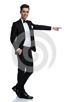 Young elegant groom smiling and pointing finger to side