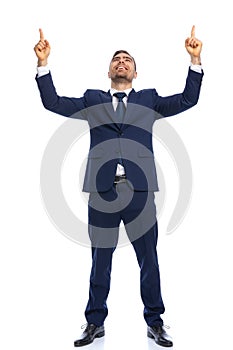 Young elegant guy in suit pointing fingers in the air and smiling