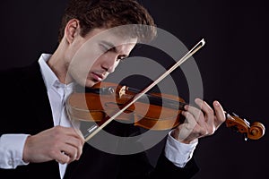 Young elegant male violinist violinist plays classical music on the violin.