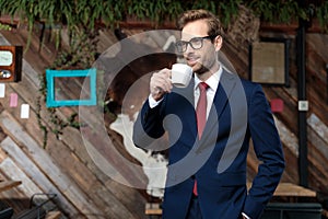 Young elegant man looking to side and drinking coffee