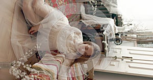 Young elegant model wearing vintage bridal dress sitting on floor, posing at home in stylish vintage interior