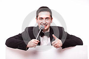 Young elegant talking man holding microphone talking on table with hands sign.