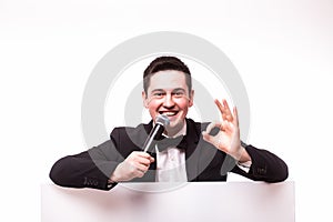 Young elegant talking man holding microphone talking on table with hands sign.