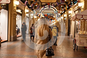 Young elegant woman with beautiful long hair with a stylish black modern bag in a fashionable autumn beige warm coat walks