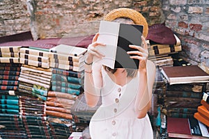 Young elegant woman choosing book in ancient secondhand bookstore Libreria Acqua Alta in Venice, Italy photo