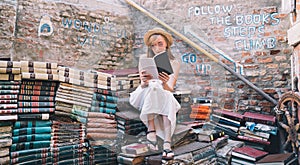 Young elegant woman choosing book in ancient secondhand bookstore Libreria Acqua Alta in Venice, Italy