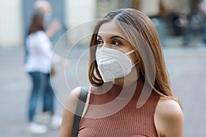 Young elegant woman in city street wearing KN95 FFP2 protective mask photo
