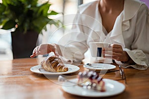 Young elegant woman drinking coffee in traditional cafe, patisserie, pastry