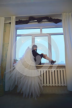 Young elegant woman in trendy black clothes with white wings. Brunette model in nice dark dress posing in studio in