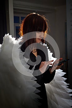 Young elegant woman in trendy black clothes with white wings. Brunette model in nice dress posing in studio in fashion
