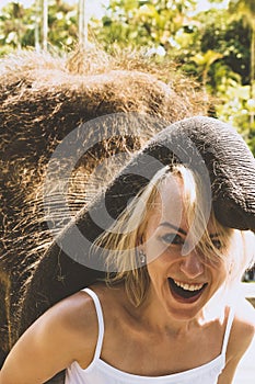 Young elephant place his trunk on woman head in Bali island