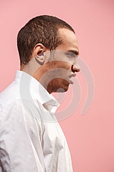 The young emotional angry man screaming on pink studio background