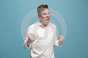The young emotional angry man screaming on studio background