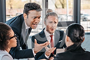 Young emotional businesspeople in formalwear arguing at meeting in office