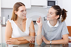 Young emotional girlfriends chatting and looking betrothal ring at home