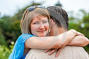 young emotional woman hugging her husband in the park