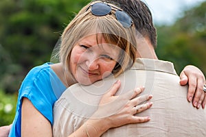 young emotional woman hugging her husband in the park