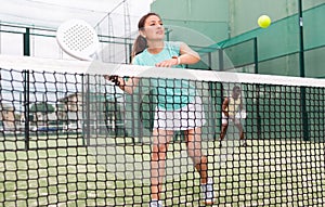 Young emotional woman playing doubles padel outdoors