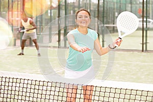 Young emotional woman playing doubles padel outdoors