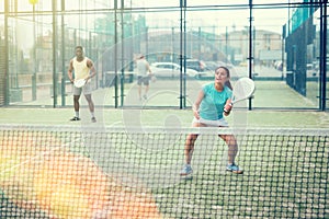 Young emotional woman playing doubles padel outdoors