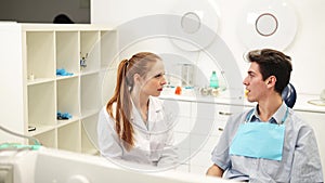 Young empathic female dentist listening to male patient complaints during dental consultation