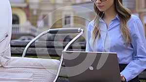 Young employed mother caring of baby while working on laptop, meeting deadline