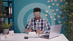 Young employee analyzing business charts on documents and laptop