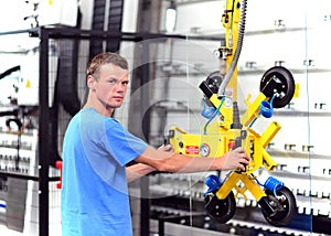 Young employee in a company manufacturing safety glass for house construction - works with a lifting tool