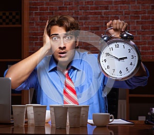 Young employee drinking coffee working at night shift