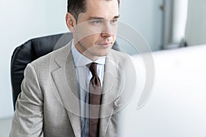 Young employee looking at computer monitor during working day in office.