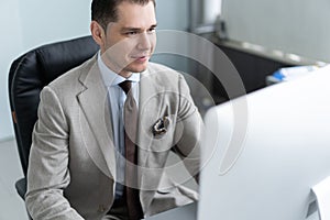 Young employee looking at computer monitor during working day in office.