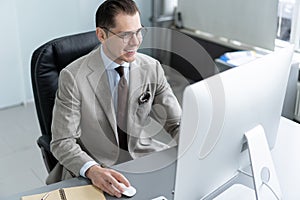 Young employee looking at computer monitor during working day in office.