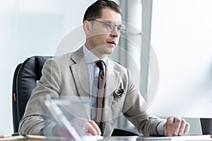 Young employee looking at computer monitor during working day in office.