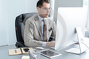 Young employee looking at computer monitor during working day in office.