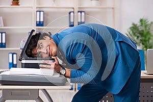 Young employee making copies at copying machine