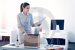 Young employee packing her stuff in box while leaving work