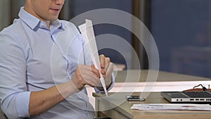 Young employee procrastinating with paper plane on working place, having fun