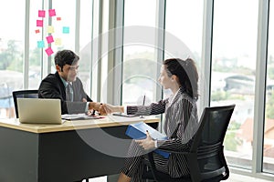 Young employers in black suits shaking hands during a meeting in the office