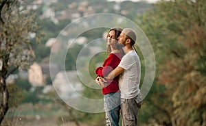 Young enamored couple stands and embraces on rest in forest.