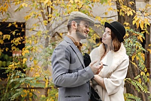 A young retro couple. Gangster guy is smoking a cigar, and the girl is looking at him in love. Outdoors.