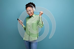 young energetic music lover latin business lady in green blouse listening to music with headphones on studio background
