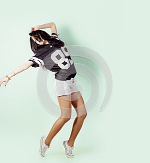 Young energetic sports active girl dancing in the Studio on a light background in t-shirt and shorts