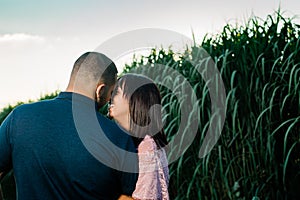 Young engaged couple outside kissing at sunset