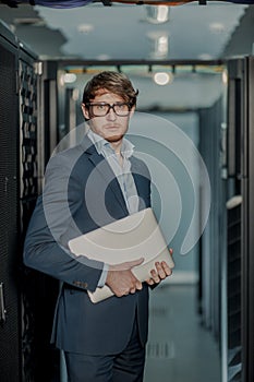 Young it engeneer business man with thin modern aluminium laptop in network server room