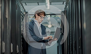 Young it engeneer business man with thin modern aluminium laptop in network server room