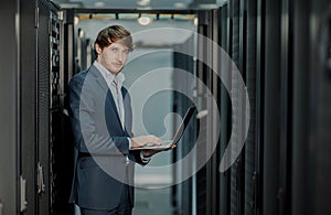 Young it engeneer business man with thin modern aluminium laptop in network server room