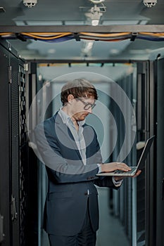 Young it engeneer business man with thin modern aluminium laptop in network server room